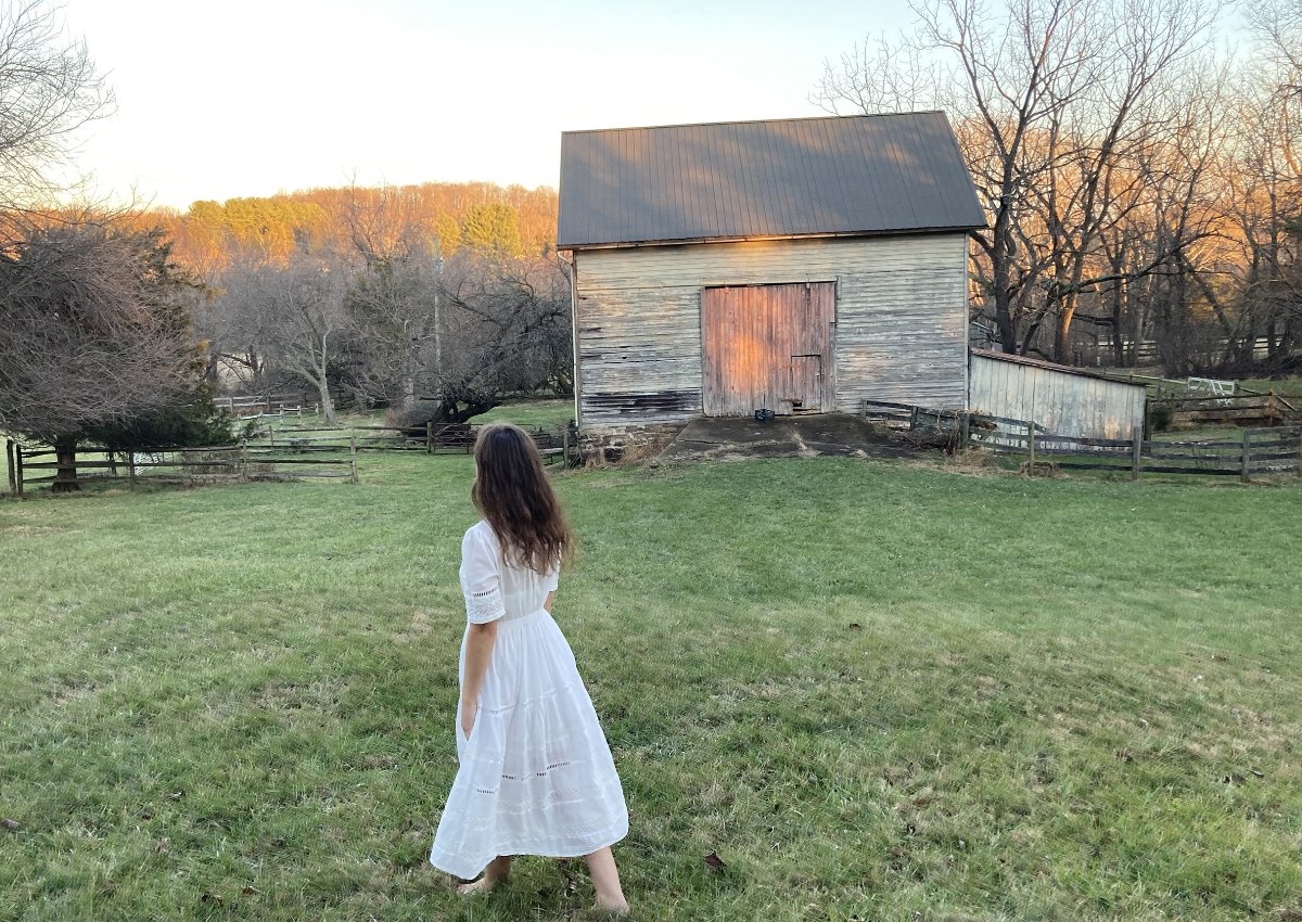 student photo of a girl in a field in front of a shed
