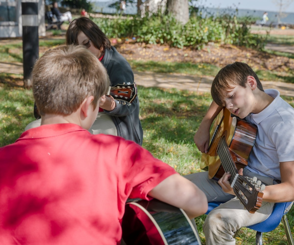 students playing acoustic guitars outside