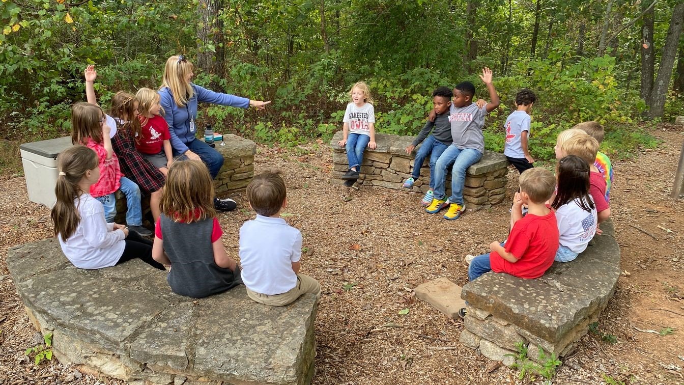 first grade teacher and students enjoying the outdoor classroom 