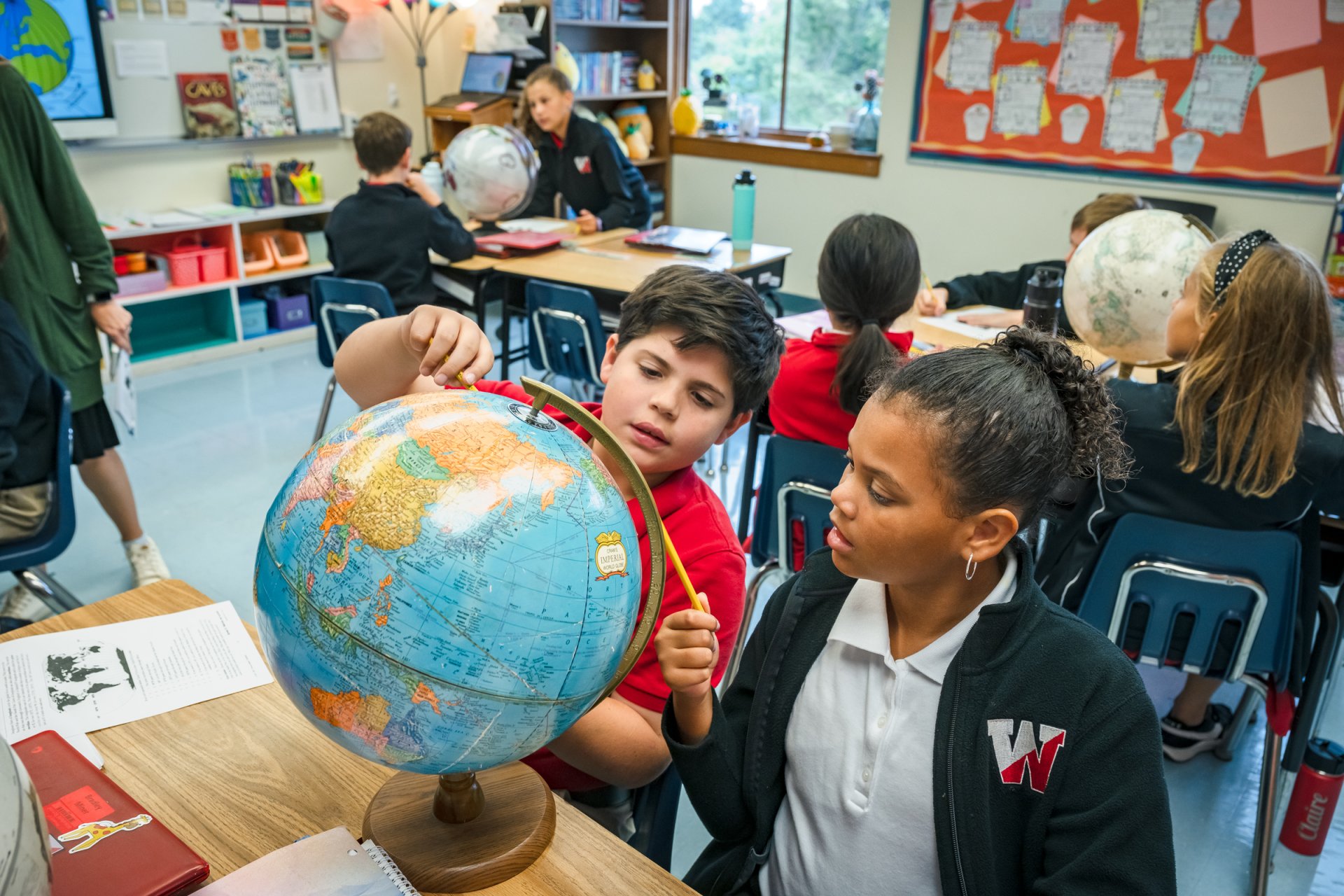 5th grade students using a globe to map geographical locations