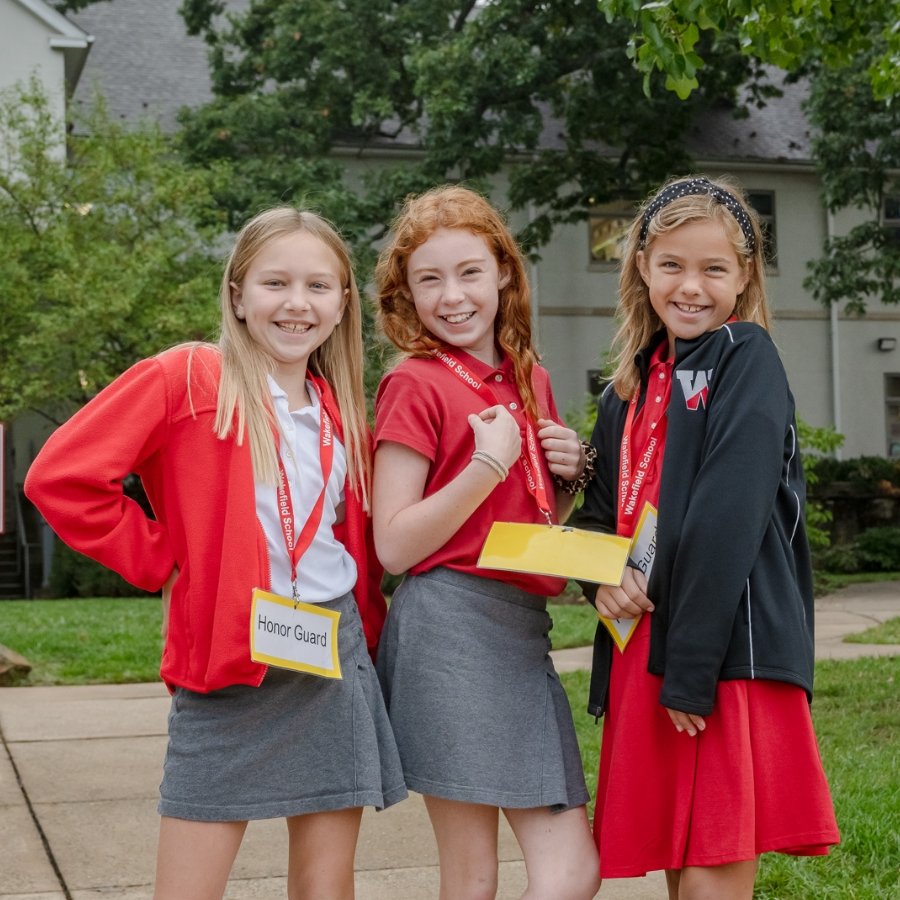 three students outside wearing nametag lanyards