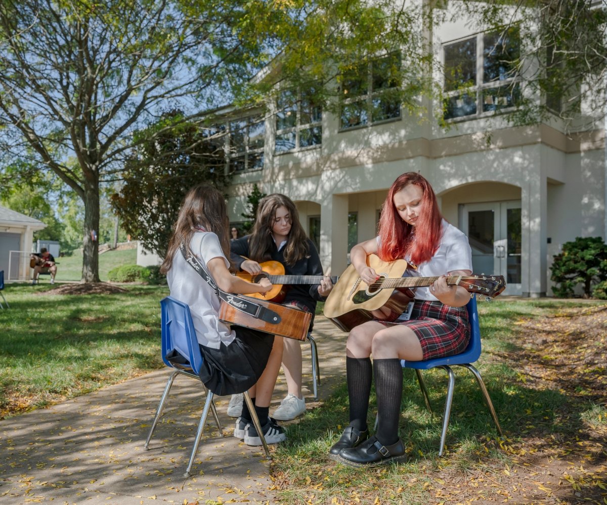 students playing acoustic guitars outside
