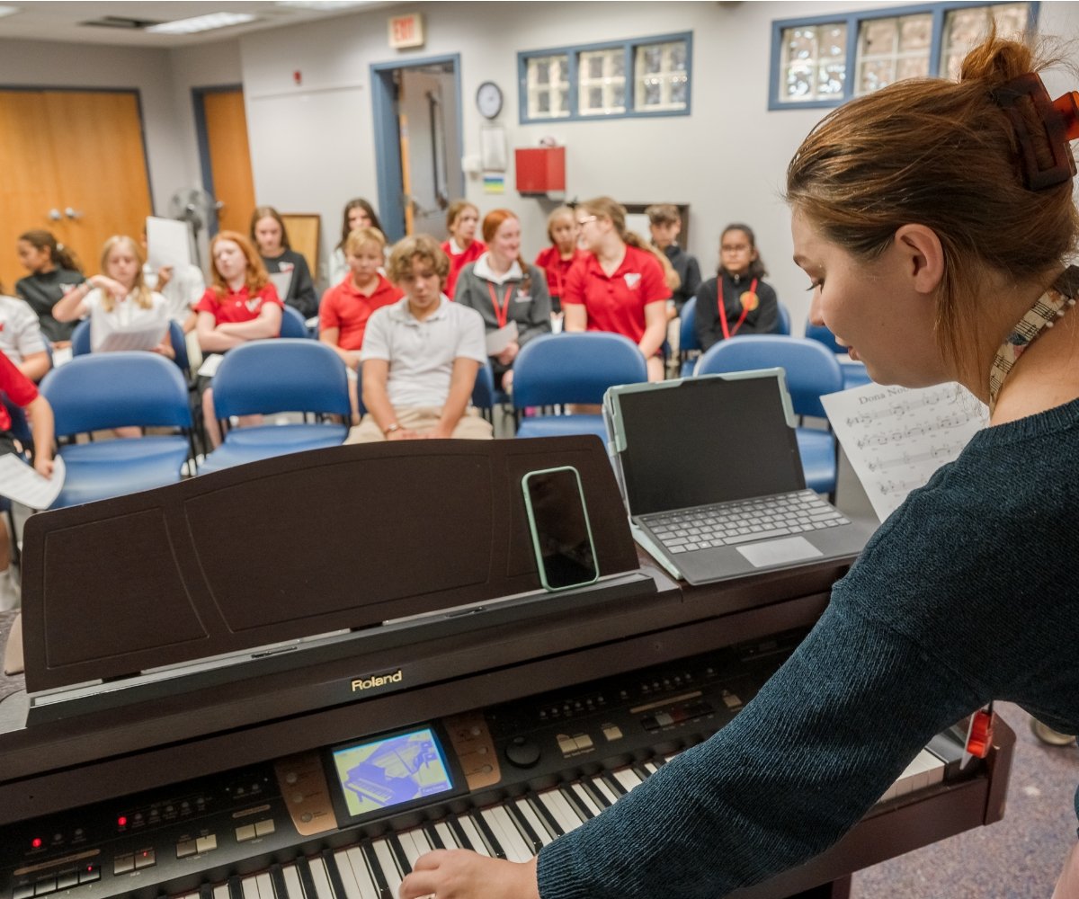 teacher playing piano for middle school choir