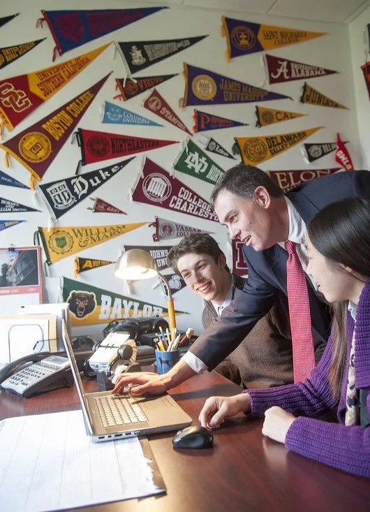 college counselor and two students looking at a laptop