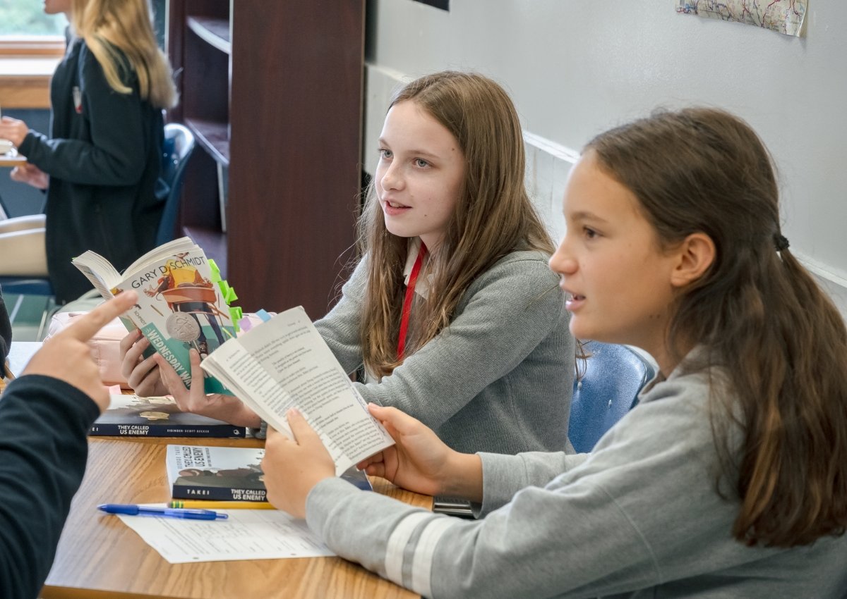 middle school students reading books and discussing