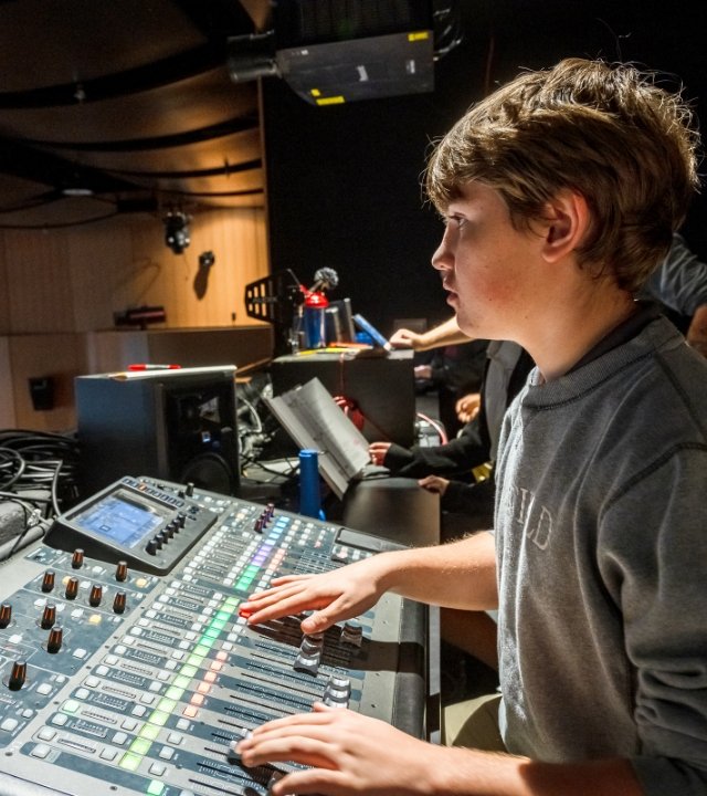 student operating the auditorium sound and lighting board